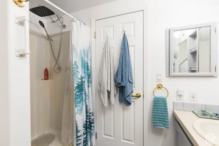 White shower enclosure featuring a square rain showerhead and handheld shower fixture