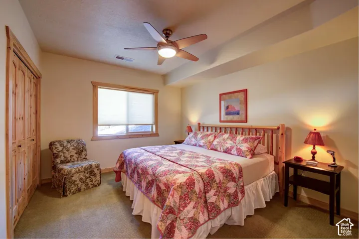 Wall-to-wall carpeting, wood-finish bi-fold closet doors, and a ceiling fan with integrated lighting