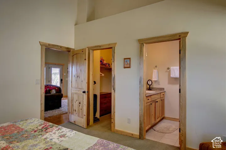 Vaulted ceiling, natural wood trim, knotty pine doors, vanity with stone countertop, and tile flooring