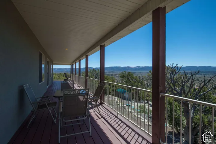 Expansive covered deck with composite wood-finish flooring, white metal railing, and sturdy support columns