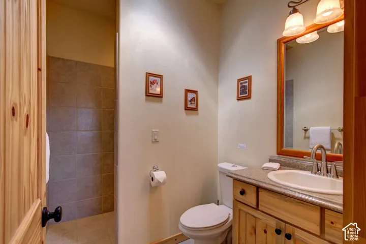 Wood vanity with dark hardware, a surface-mounted sink, and a framed mirror