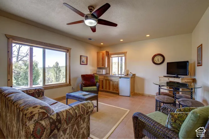 Spacious room featuring a ceiling fan, recessed lighting, and large windows with wood trim