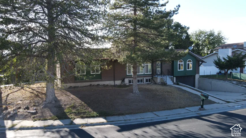 Brick exterior with a prominent arched window, integrated garage, and mature trees