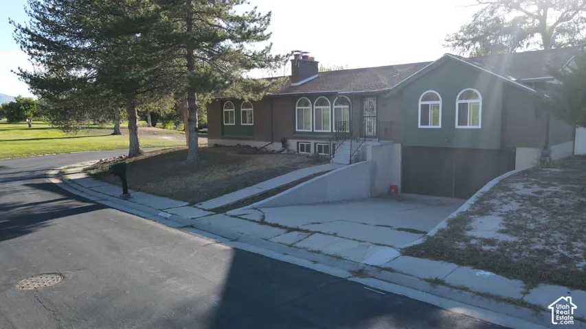 Property exterior featuring arched windows, a multi-pane front entry door, a multi-car garage, mature trees, and a paved driveway