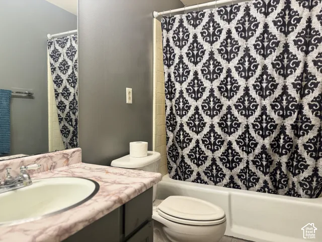 Bathroom featuring a vanity with a drop-in sink, a built-in bathtub, and a toilet