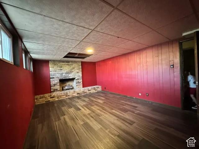 Brick fireplace with hearth, wood-finish flooring, and drop ceiling