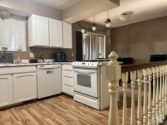 Kitchen featuring wood-finish flooring, white cabinetry, a white dishwasher, a white range, and a patterned countertop