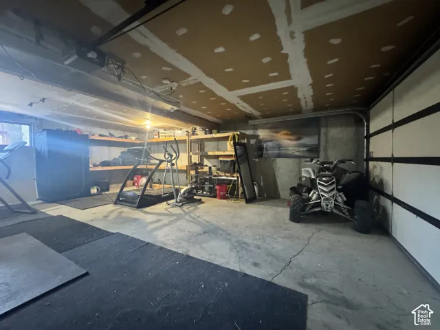 Concrete flooring with rubber matting, exposed ceiling joists, and built-in shelving