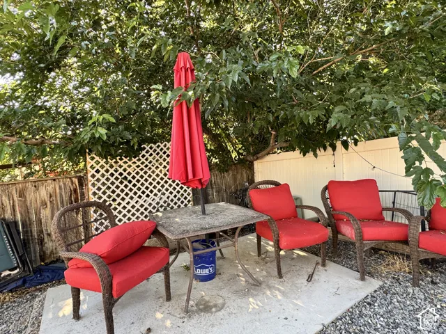 Patio area with concrete pavers, mature tree for shade, wood lattice fencing, and a privacy fence