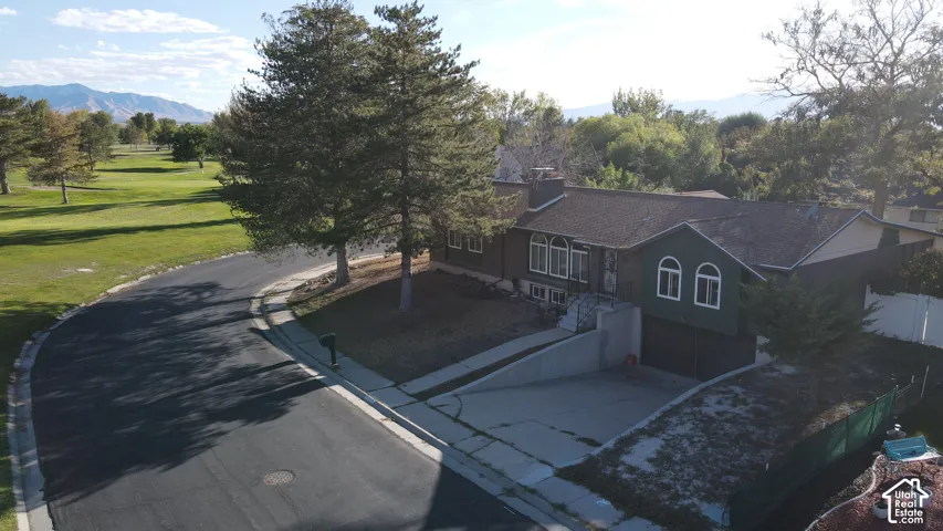 Curb appeal featuring a multi-level design, attached garage, and mature trees