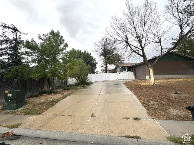 Paved driveway leading to the property, featuring a white privacy fence and a dark wood privacy fence