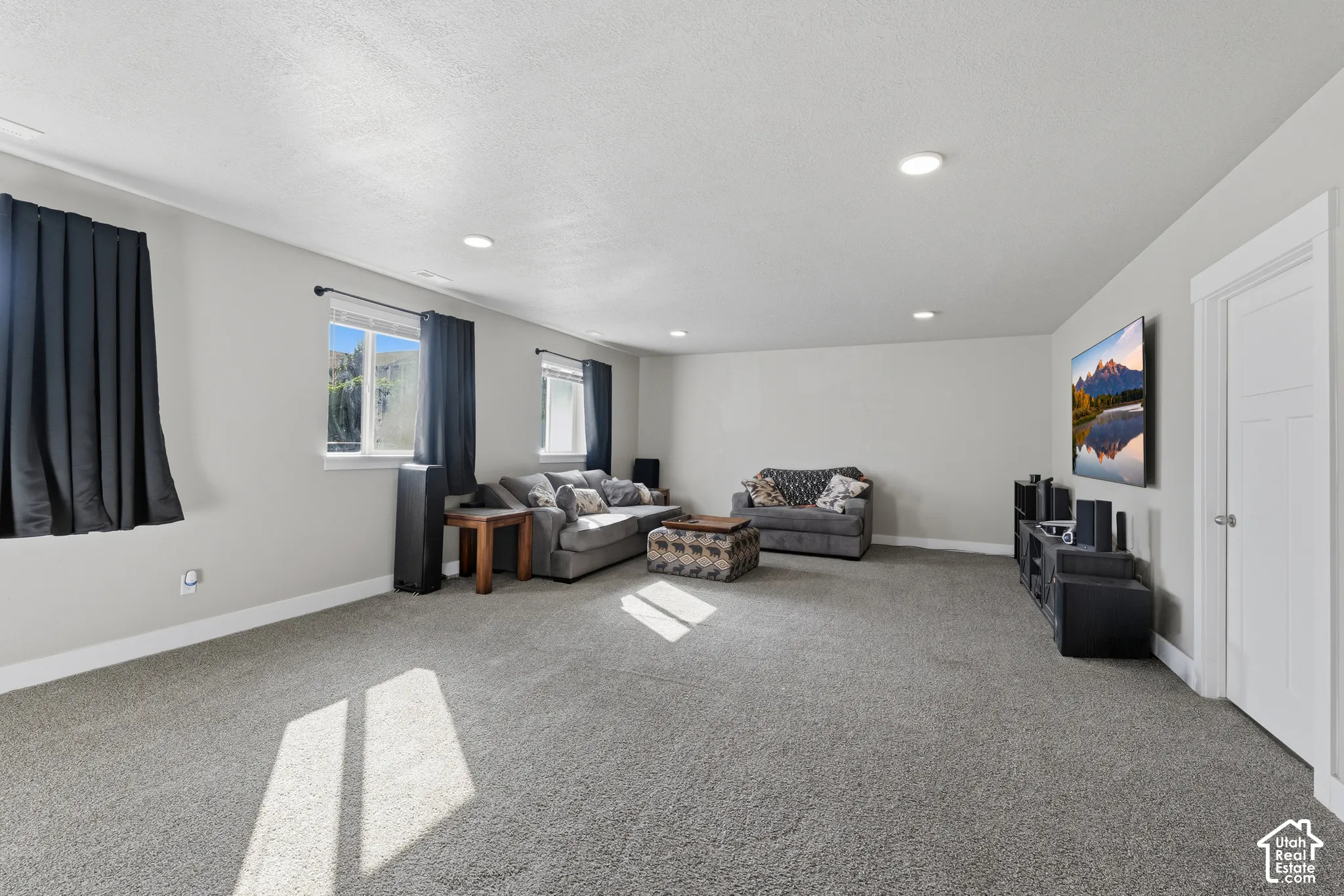 Spacious interior featuring recessed lighting, neutral wall paint, carpeted flooring, and a multi-panel interior door