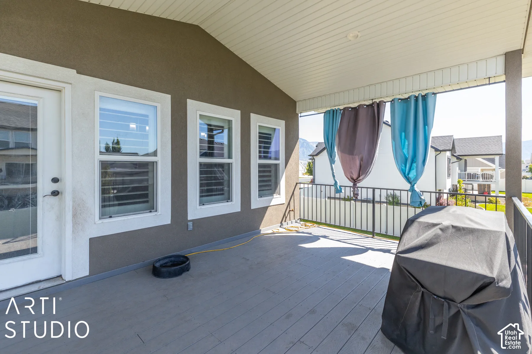 Covered outdoor patio featuring composite decking, a white railing, and exterior wall siding