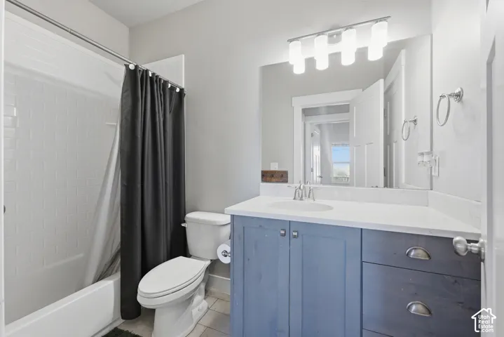 Bathroom featuring a custom blue-finish vanity with a white countertop, subway tile shower surround, four-bulb vanity lighting, and large wall-mounted mirror