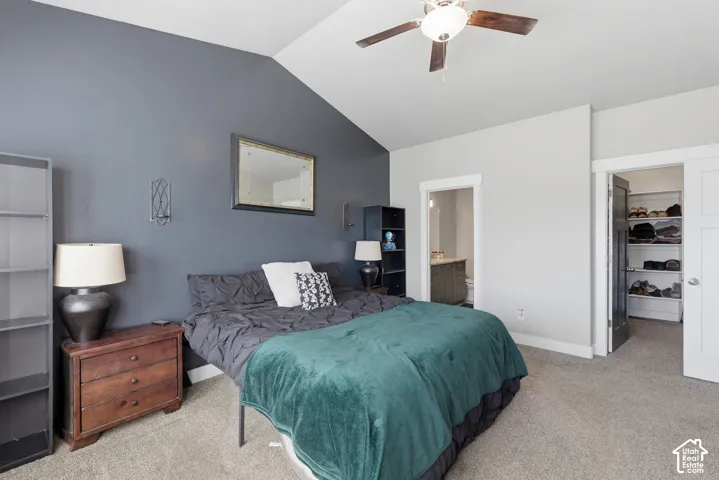 Vaulted ceiling, accent wall, ceiling fan with light kit, and walk-in closet with built-in shelving