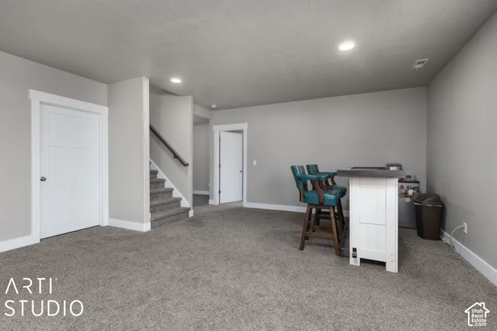 Carpeted flooring, recessed lighting, white interior doors, and staircase with a dark wood handrail