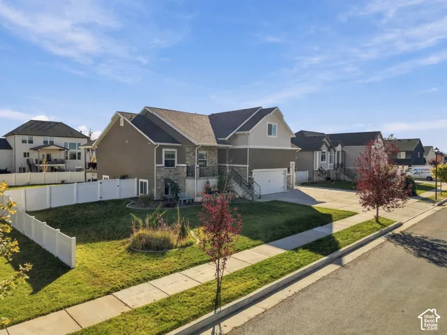 Two-story residence featuring a mixed stucco and stone veneer exterior, an attached two-car garage, and a fenced side yard with a concrete driveway