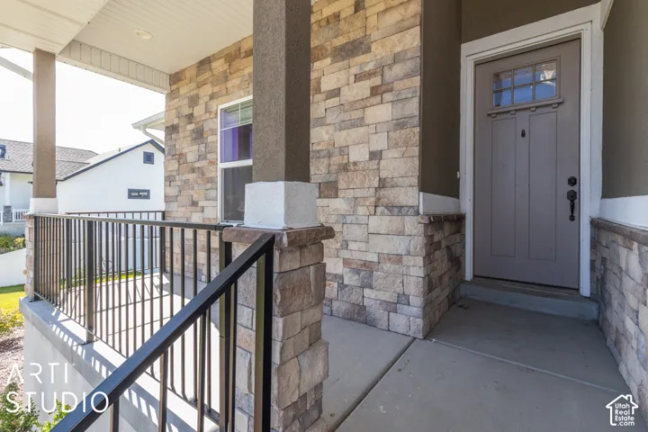Stone veneer facade with stucco accents, leading to a front entry door with transom window and black hardware