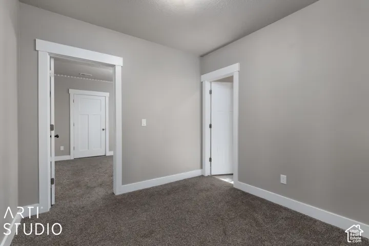 Neutral-toned walls with contrasting white trim, plush carpet flooring, and a white interior door with dark hardware
