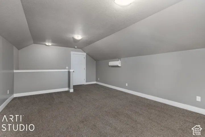 Spacious loft area featuring sloped ceilings, recessed lighting, and soft carpet flooring