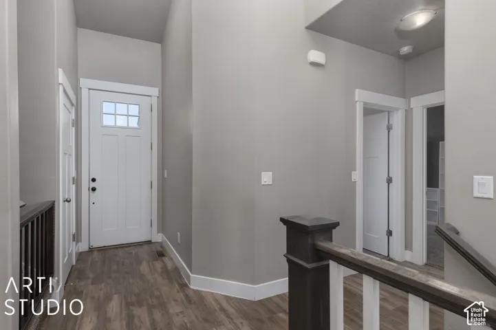 Recessed entry featuring a white paneled door with divided lites, wood-finish flooring, and white trim