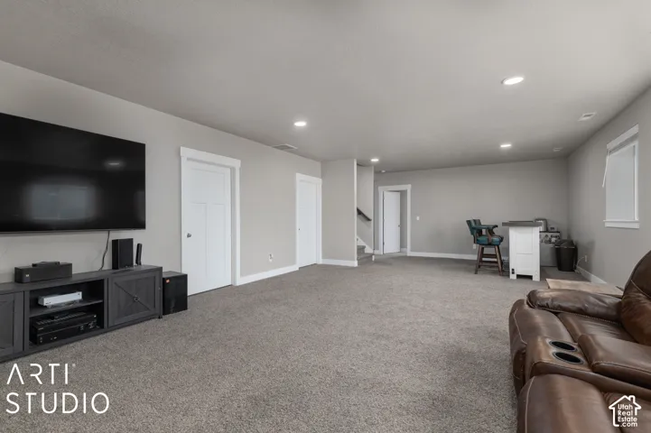 Recessed lighting throughout, plush carpeting, built-in entertainment console, white paneled doors, and a built-in wet bar