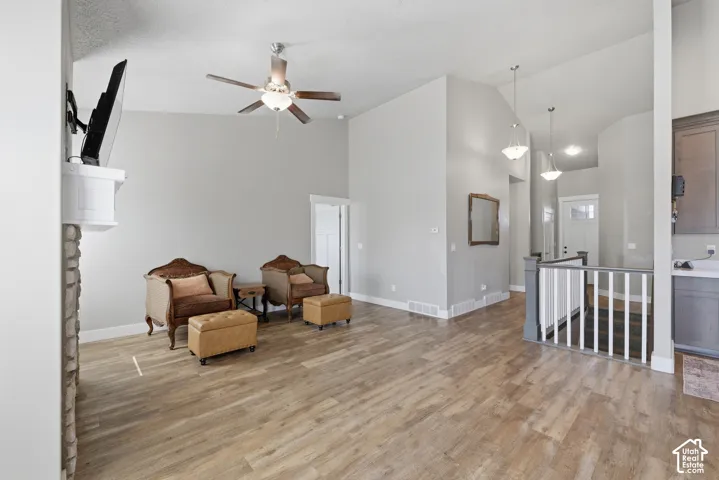 Vaulted ceilings featuring a stone-clad fireplace, wood-finish flooring, and pendant lighting
