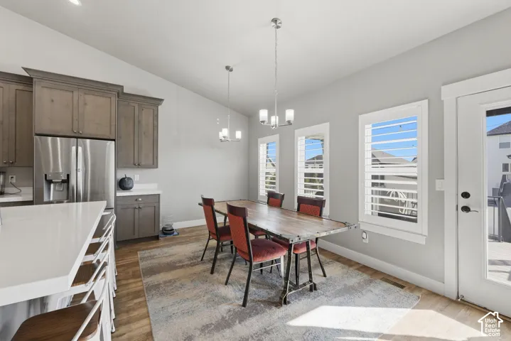 Kitchen featuring wood-finish cabinetry, quartz countertops, wood-finish flooring, vaulted ceilings, and window shutters