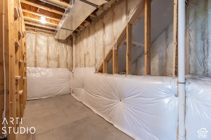 Unfinished basement featuring exposed wood framing, concrete flooring, and insulated walls