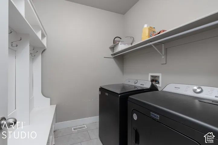 Built-in storage bench with coat hooks, floating wall shelf, and tile flooring