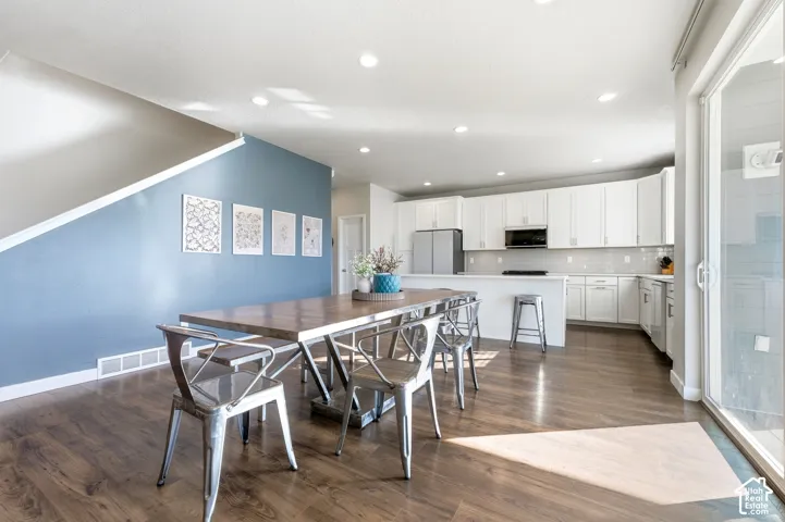 Open-concept living space featuring wood-finish flooring, recessed lighting, and a sliding glass door