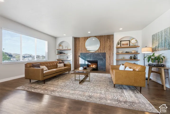 Recessed lighting, wood-finish flooring, large windows, built-in shelving, and a fireplace with a black stone surround