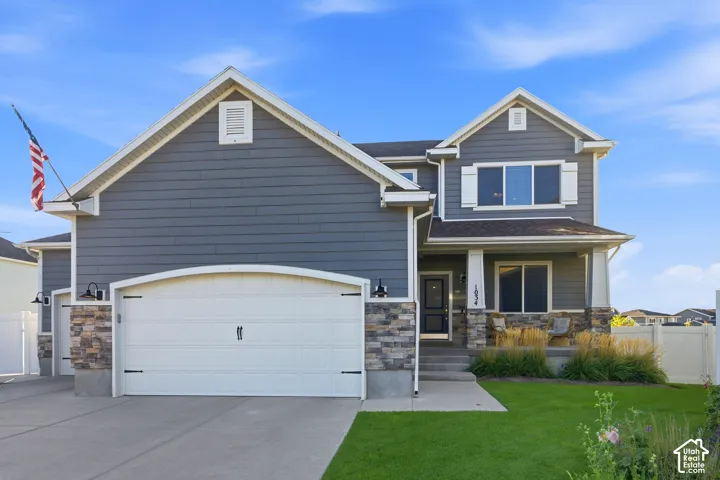 Two-story residence featuring a covered entry, stacked stone accents, and a two-car garage with an arched door