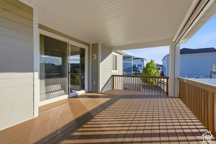 Spacious covered deck with durable wood-finish flooring, white ceiling, and a sliding glass door