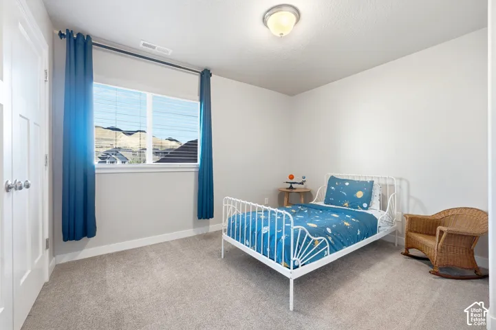 Neutral wall finishes, recessed window with blinds, carpeted flooring, overhead flush-mount lighting, and a paneled door with round hardware