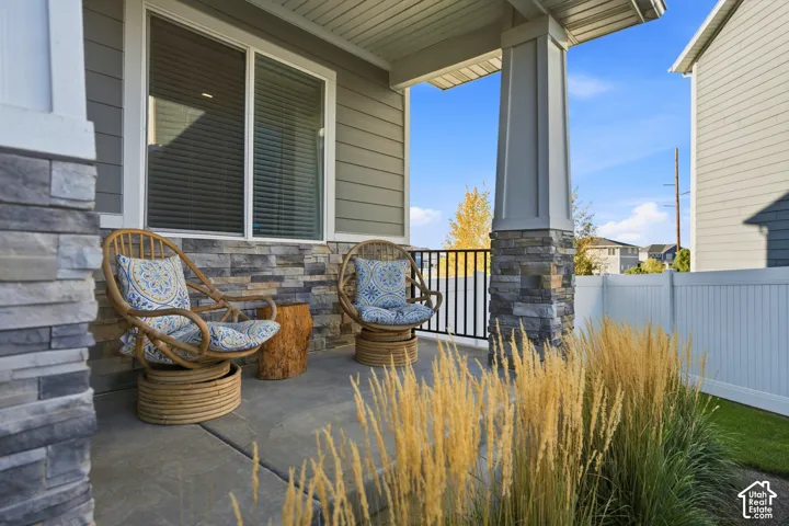 Inviting front porch featuring a concrete surface, stone veneer accents, and a black metal railing