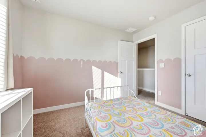 Carpeted flooring, white trim details, window with blinds, panel doors, and built-in closet shelving