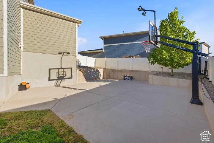 Expansive concrete patio with a permanent basketball hoop featuring overhead lighting