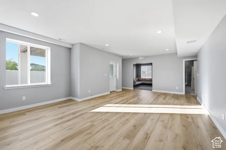 Recessed lighting, wood-finish flooring, light gray wall paint, white trim, and a white interior door