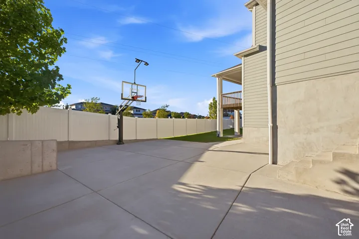 Expansive concrete pad, privacy fencing, side yard with green space, covered deck, and exterior siding