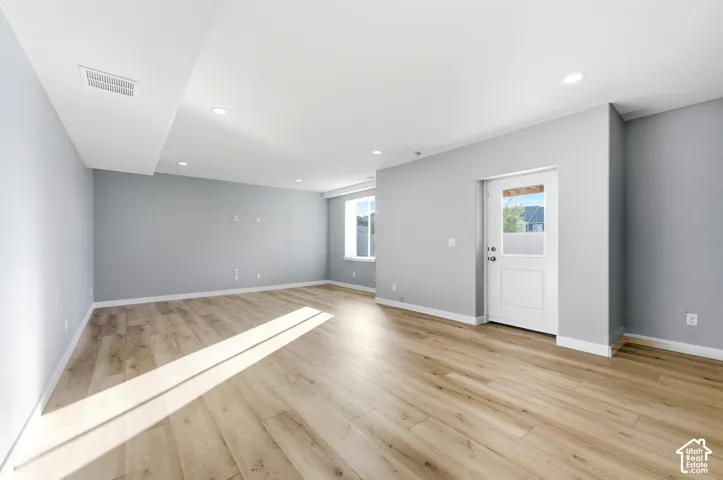 Expansive room featuring recessed lighting, light wood-finish flooring, and multiple windows