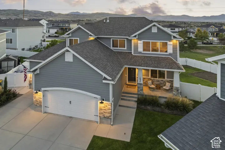 Siding exterior with stone accents, a covered front porch, and a two-car garage