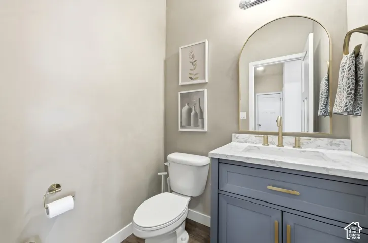 Guest bathroom Integrated vanity with a white countertop and undermount sink, brass finish fixtures, and a gold-framed arched mirror