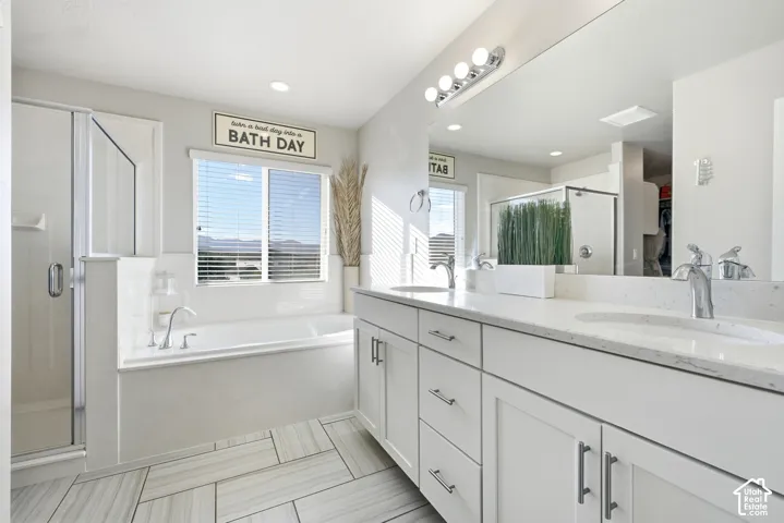 Primary en suite Dual vanity with undermount sinks, a built-in bathtub, a walk-in shower with clear glass enclosure, and large format floor tile