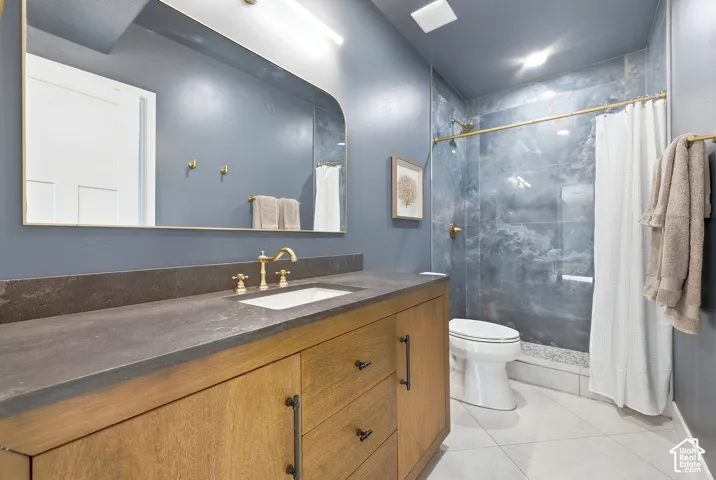Wood-finish vanity with an integrated sink, dark countertop, and brass fixtures