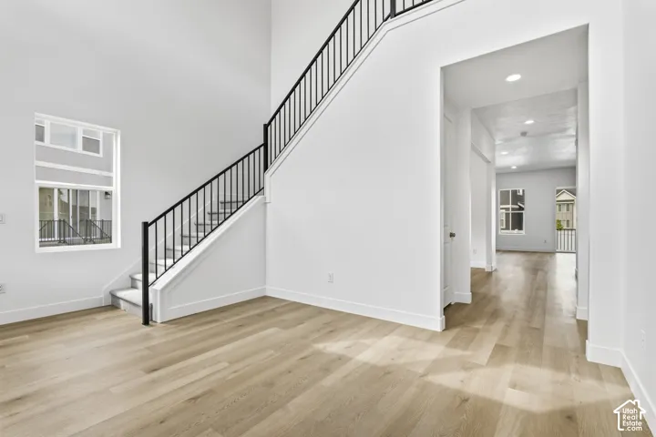 Two-story entryway featuring wood-finish flooring, a contemporary staircase with black wrought iron spindles, and high ceilings