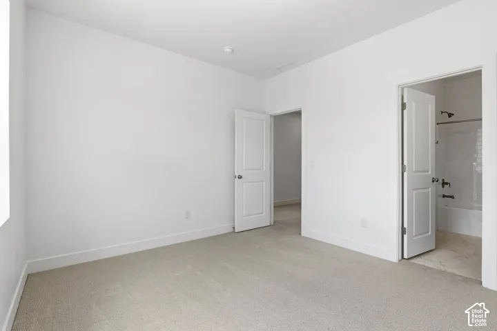 Plush carpeted flooring, white interior doors, and modern overhead lighting