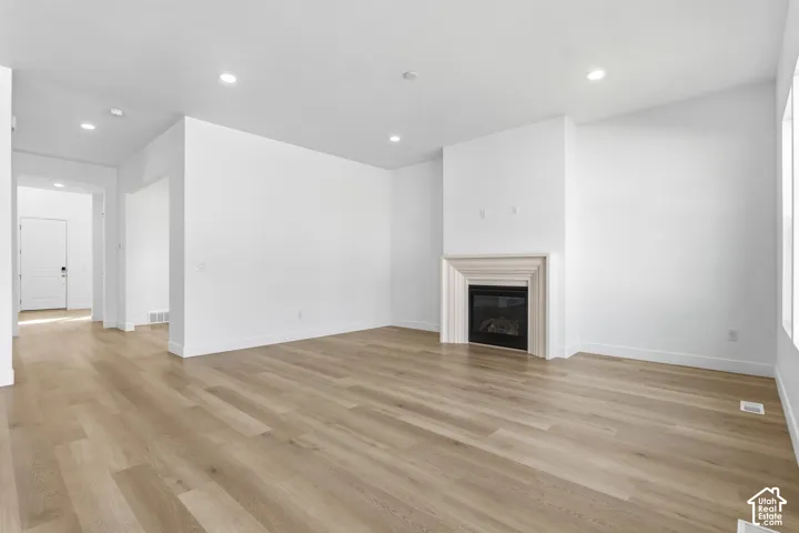 Spacious room featuring wood-finish flooring, recessed lighting, and a contemporary fireplace with a decorative mantel