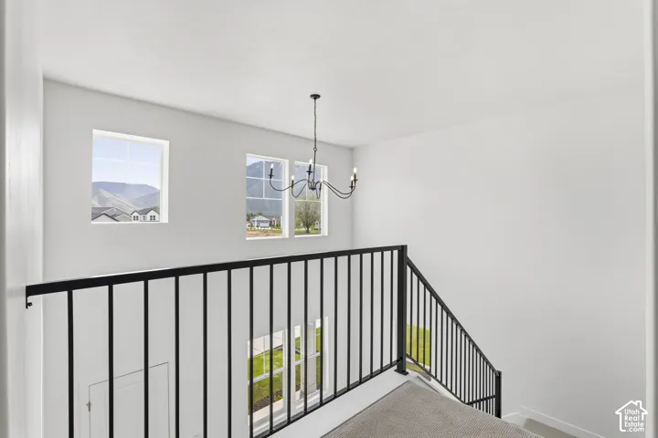 Black iron railing, white walls, black chandelier, and carpeted stairs