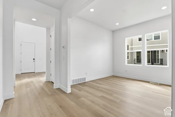Recessed lighting illuminates wood-finish flooring and white walls